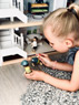 Kind spielt mit Puppenhaus aus Holz und Spielfiguren